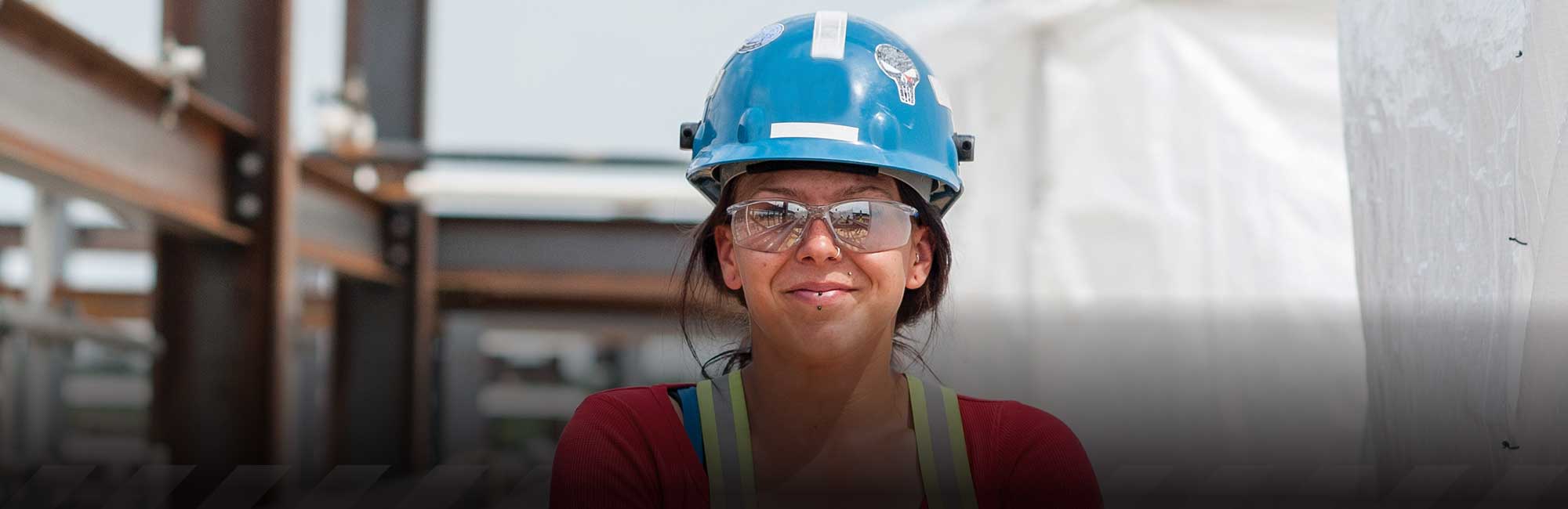 a woman in a red shirt and safety vest with a blue hard hat