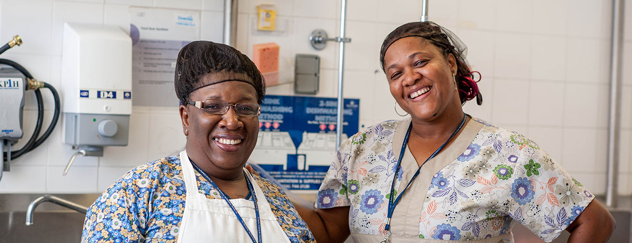 two smiling woman in scrubs in a kitchen